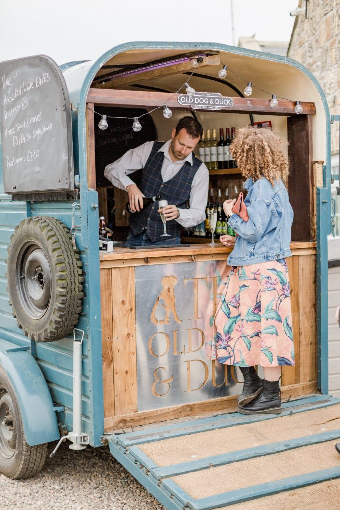 barman at horse box bar pouring wedding guest a drink