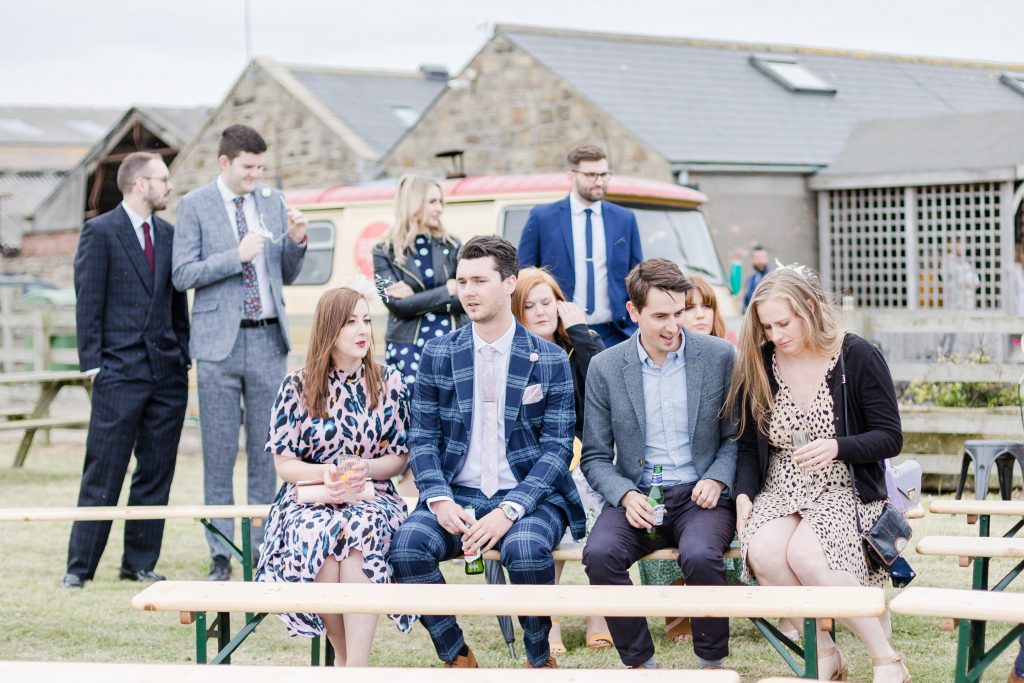 wedding guests sat on bench at festival style wedding