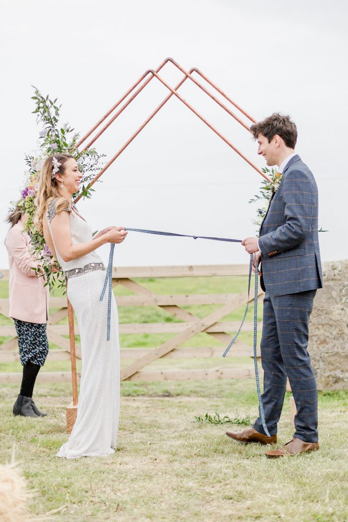 bride and groom pulling Scottish ribbon laughing for hand tying ceremony