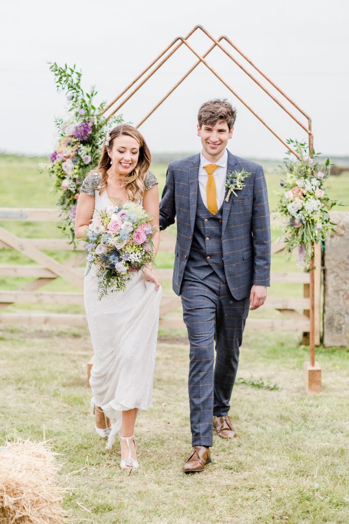 bride and groom walking away from copper arch alter down the aisle