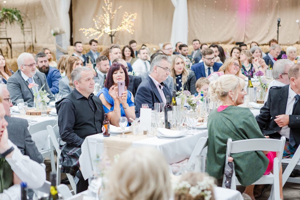 guests in barn wedding listening to speech by brother of groom