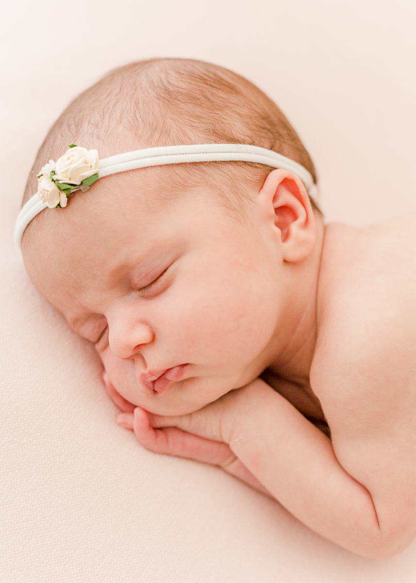 newborn asleep on side with hairband close up