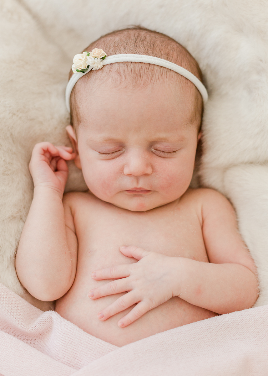 newborn asleep on cream fur with headband