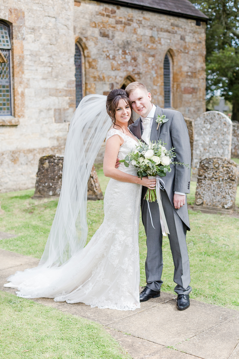 bride and groom pose together outside church vail in the air