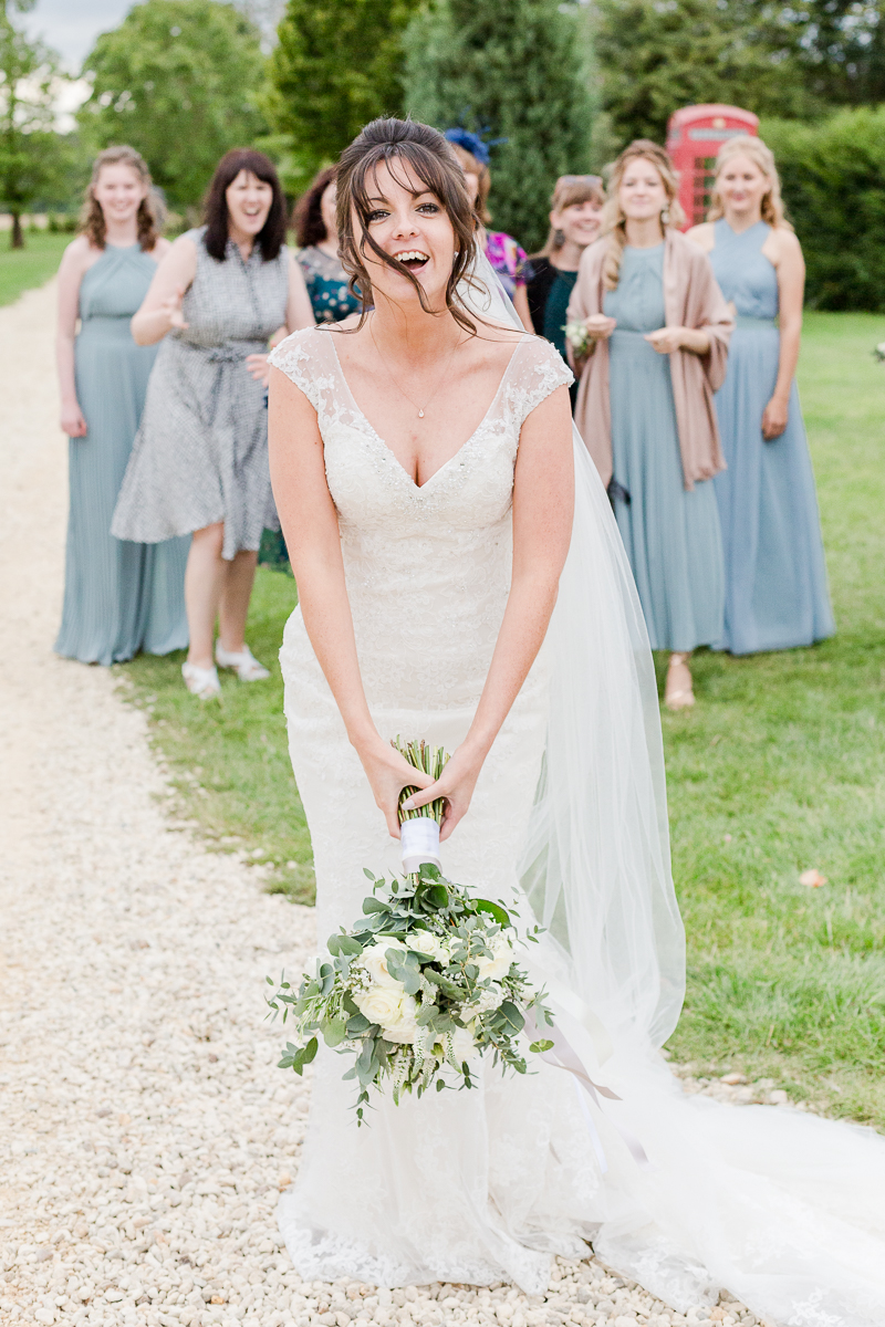 bride about to throw bouquet with female guests behind