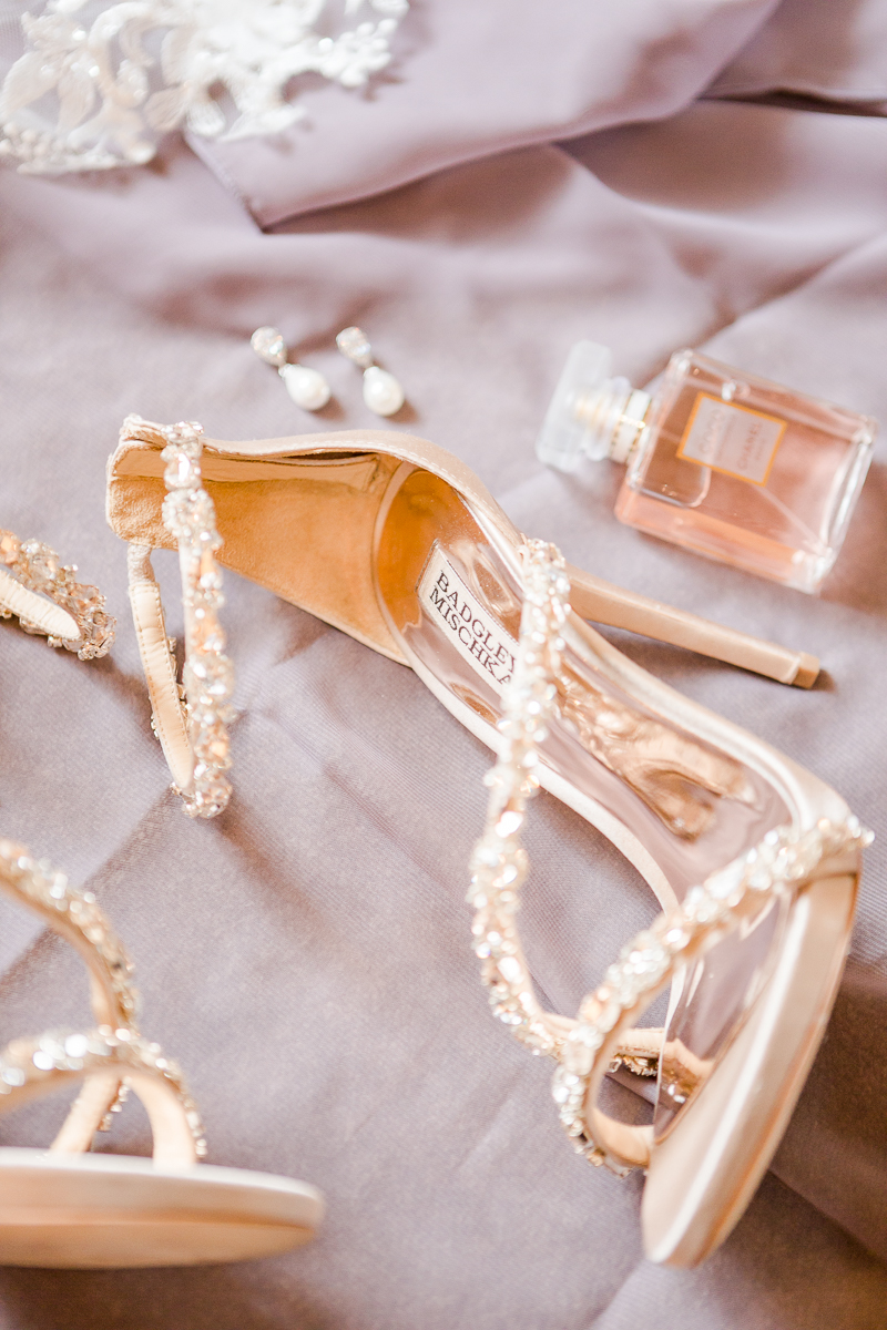 wedding shoes displayed on floor with earrings and perfume