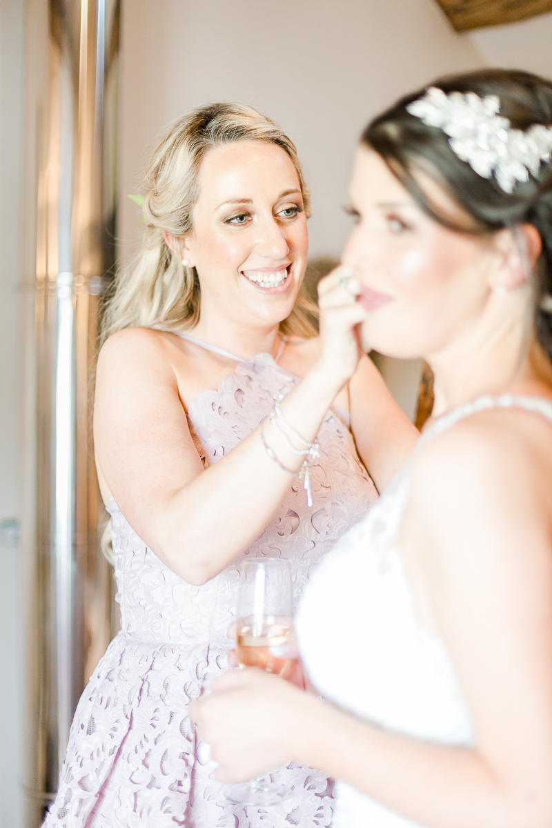 bridesmaid putting brides earrings in