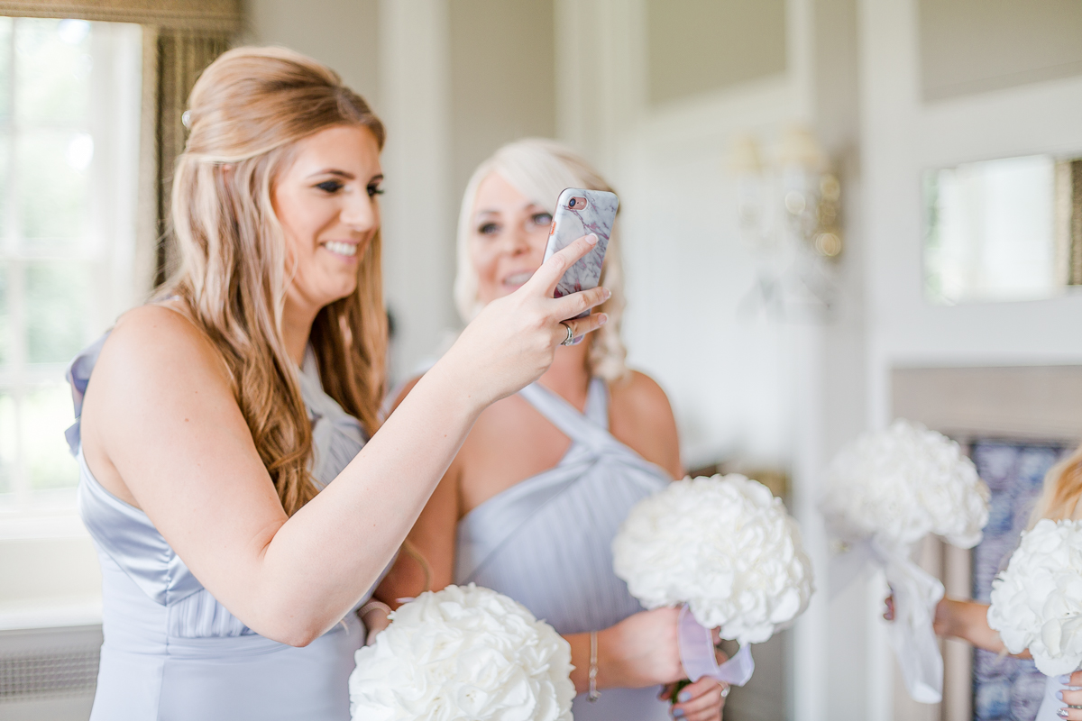 bridesmaids taking photo with phone camera laughing