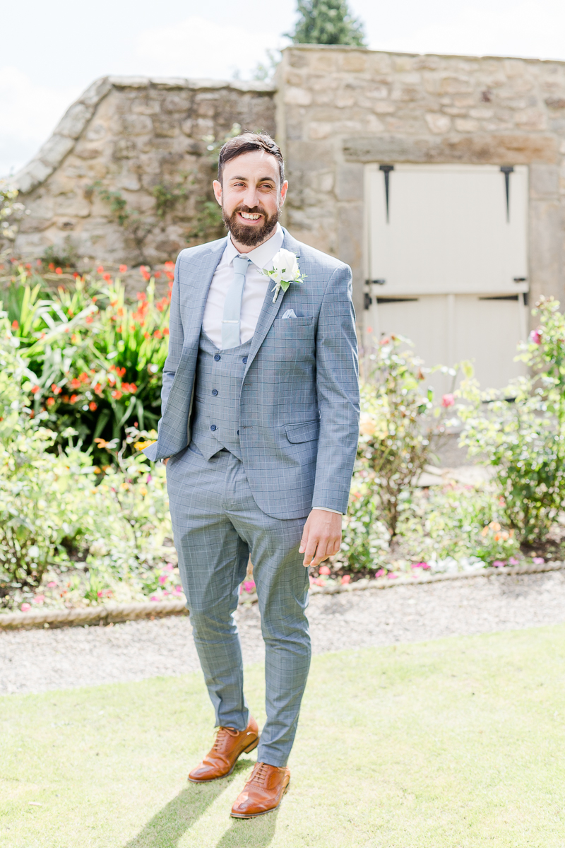 groom wearing grey blue suit in gardens