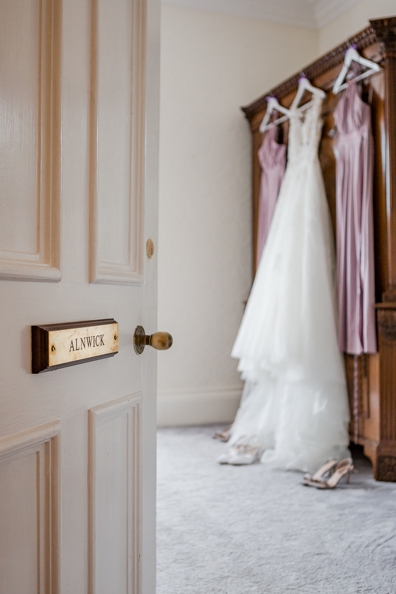 wedding dress and purple bridesmaids dresses hanging on wardrobe