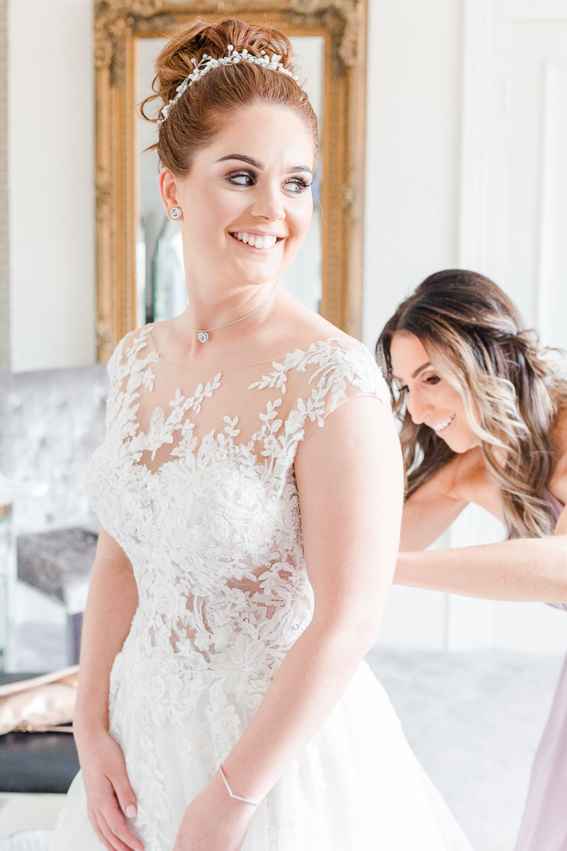 bride having wedding dress fastened