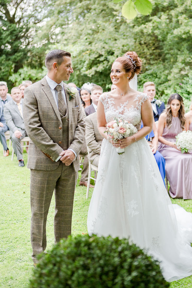 bride smiling at groom at alter