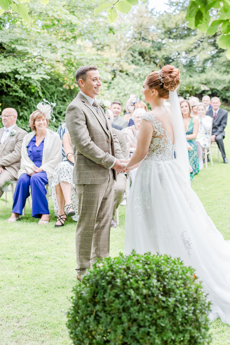 bride and groom at alter looking at each other with guests in background