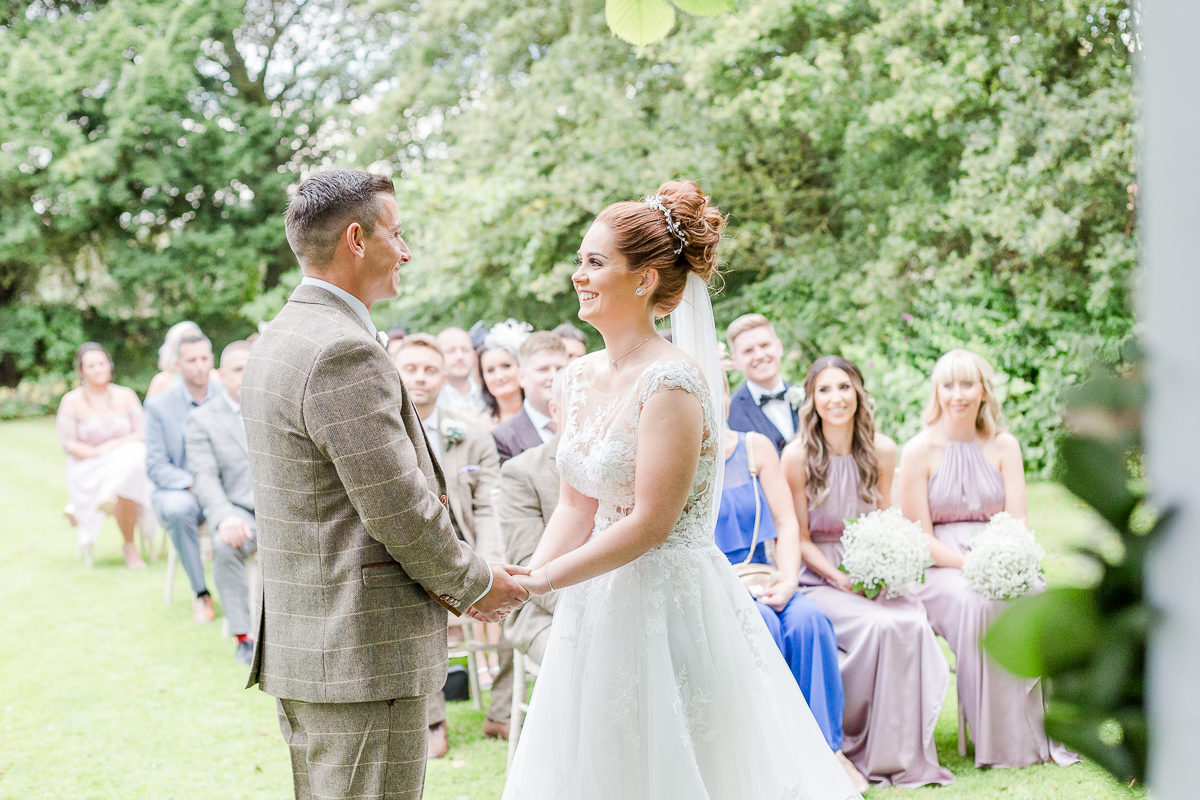 bride and groom face each other at alter