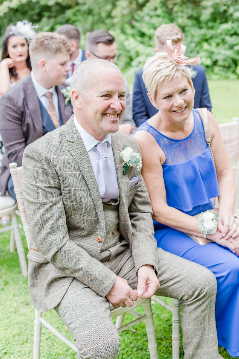 brides parents sat watching and smiling