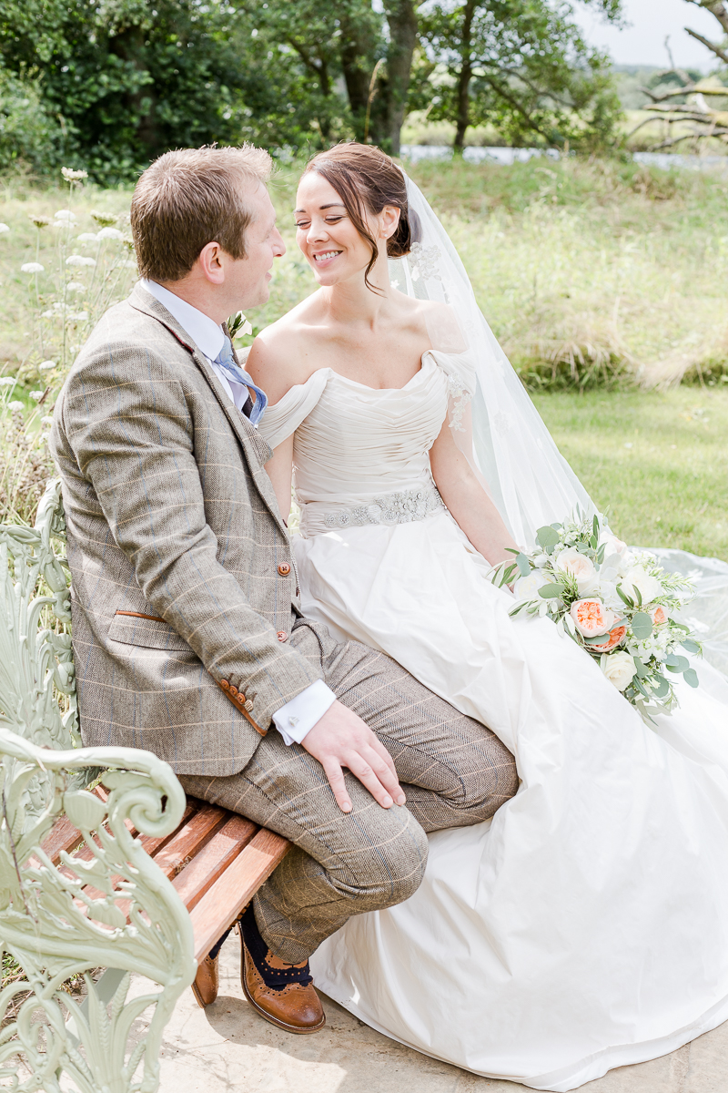 bride and groom on bench looking at each other