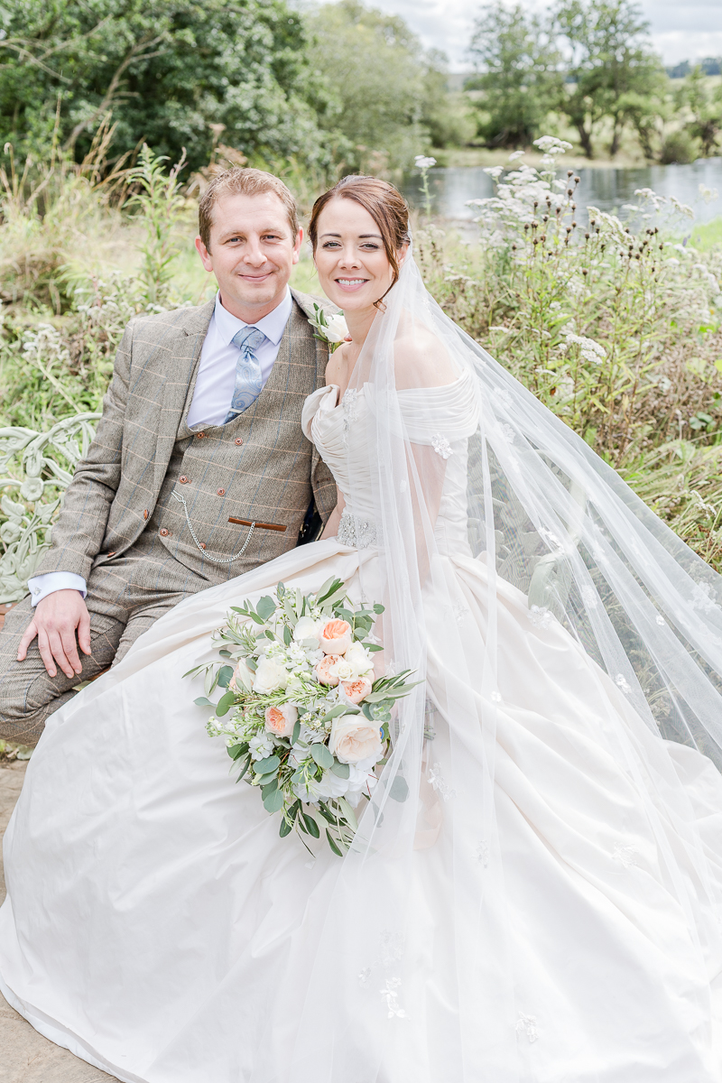 bride and groom on bench with dress displayed