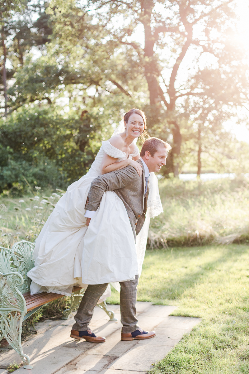 bride has piggy back on groom in field