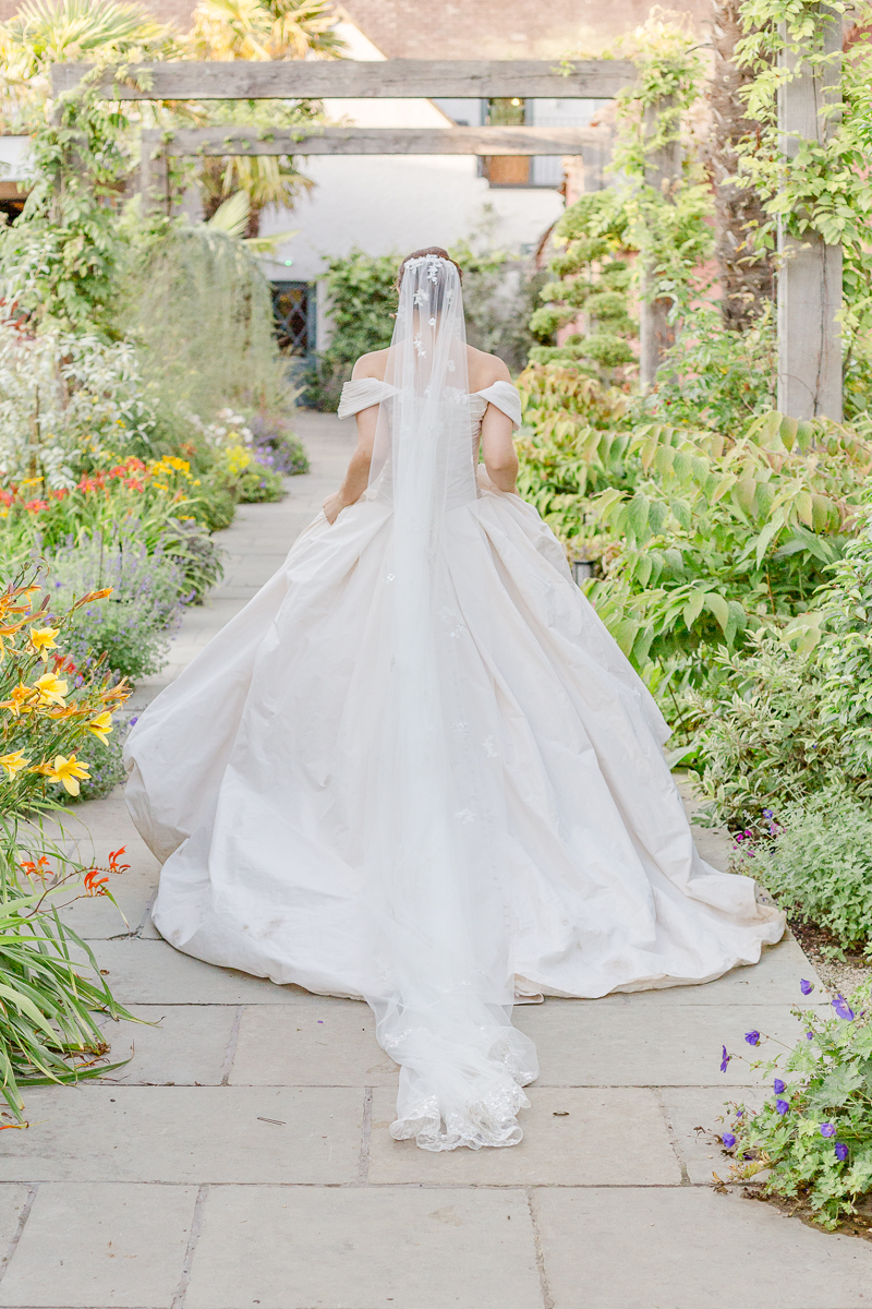 bride and big wedding dress walk through flower garden