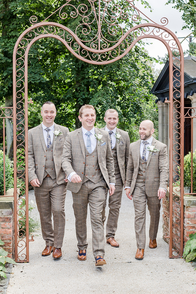 groom and batsmen walking under venue arch