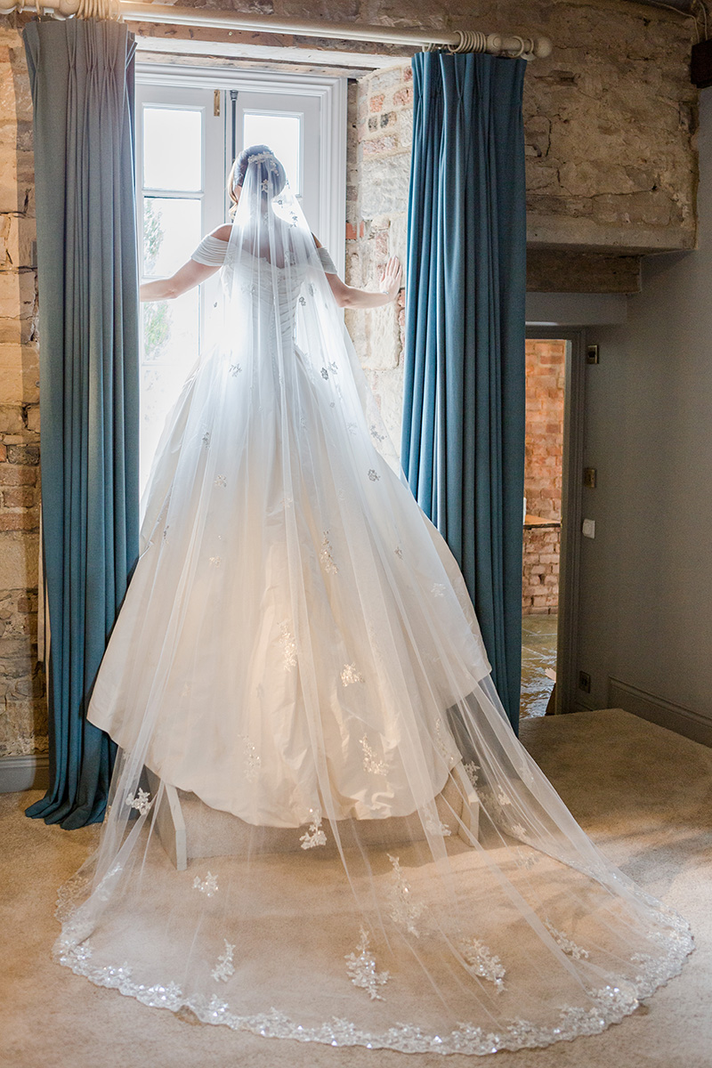 back of brides gown flowing down steps in window