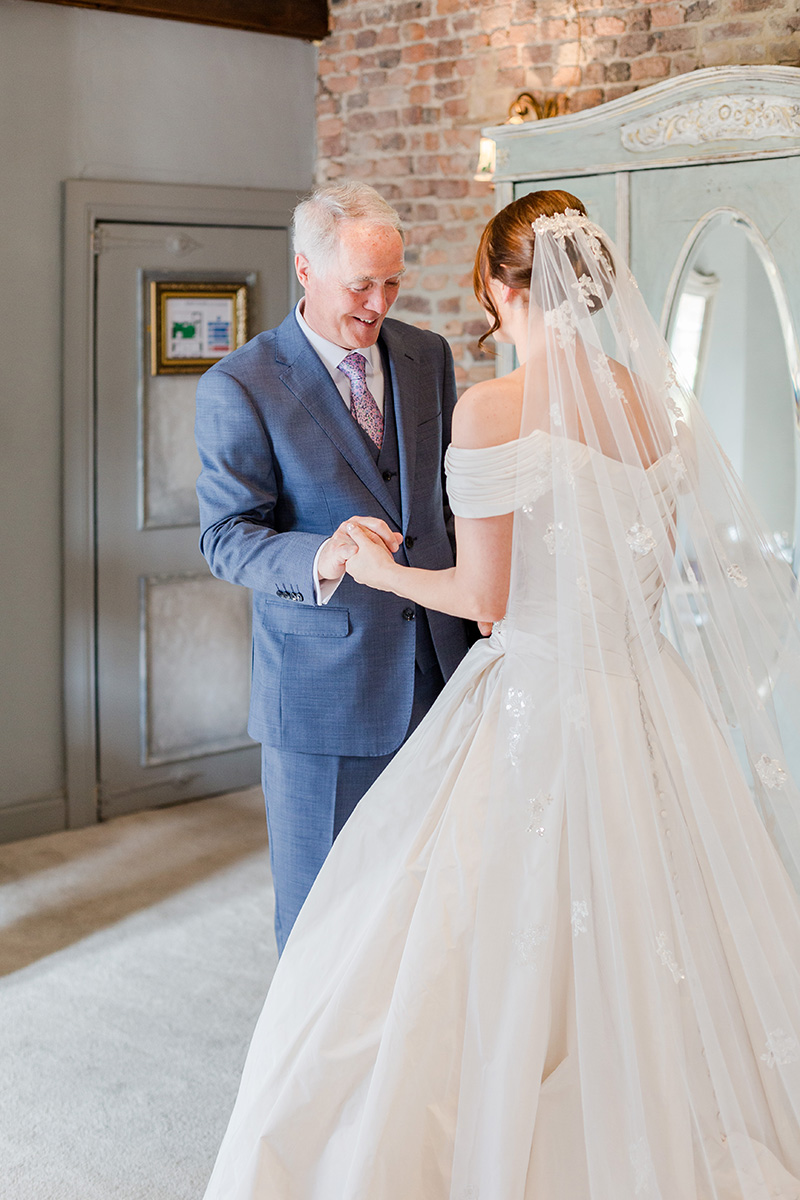 father and bride hold hands