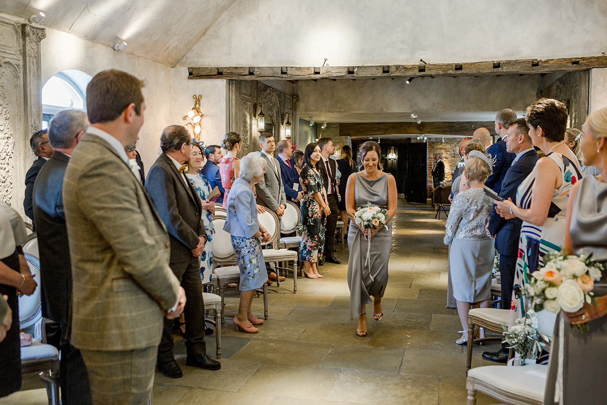 groom watches bridesmaid walking down aisle