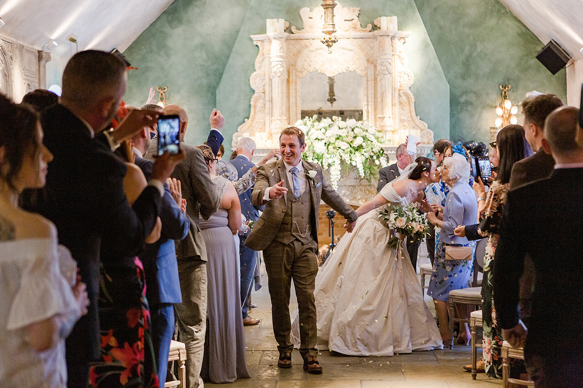 bride and groom walk back up aisle under confetti