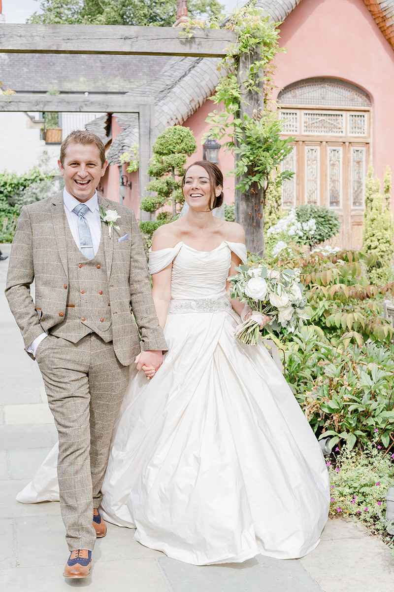 bride and groom hand in hand walking through gardens