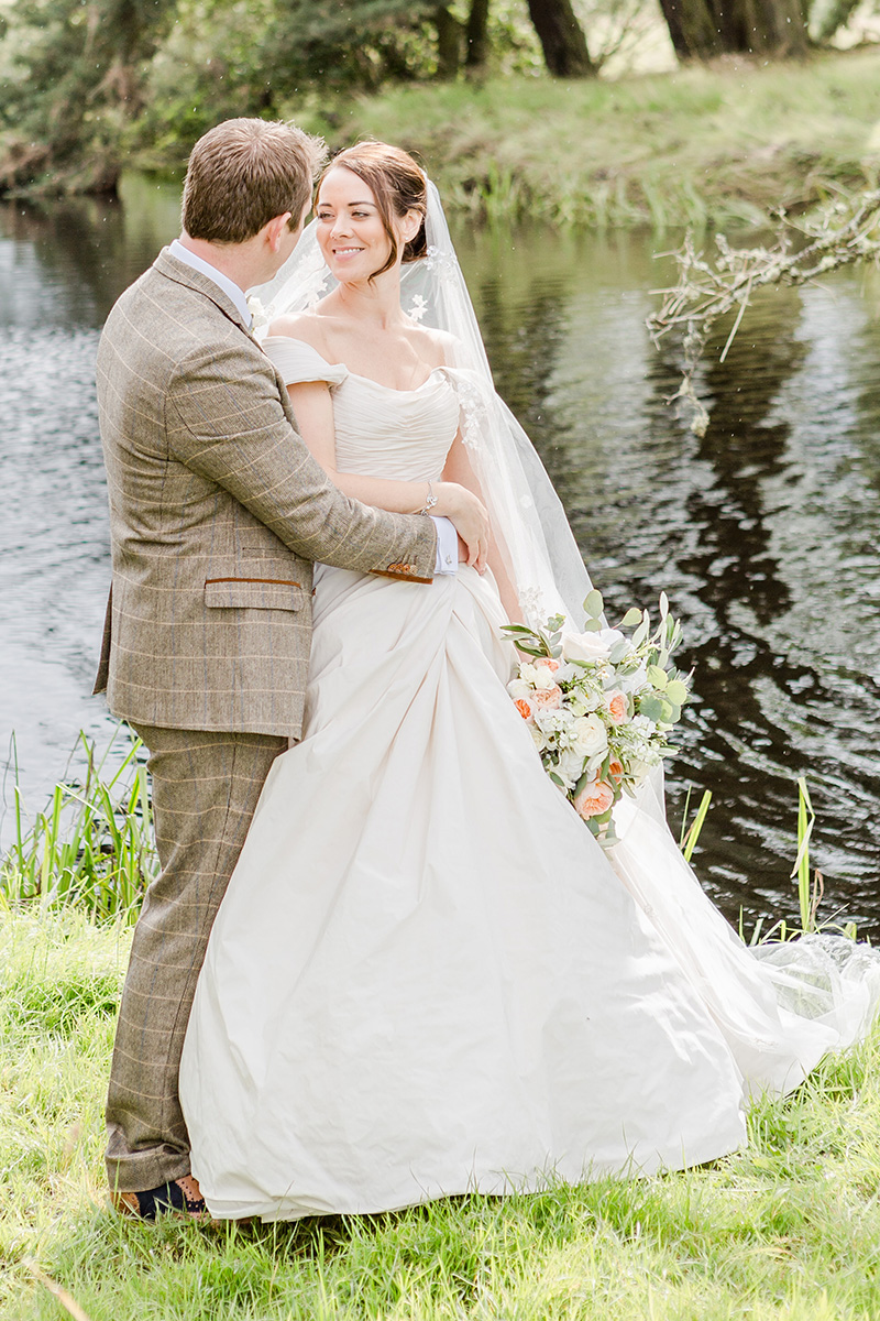 bride and groom infant of lake with arms around each other