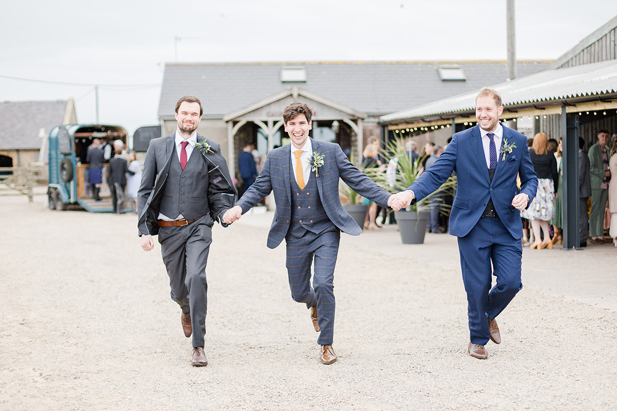 groom and two bestmen skipping towards camera