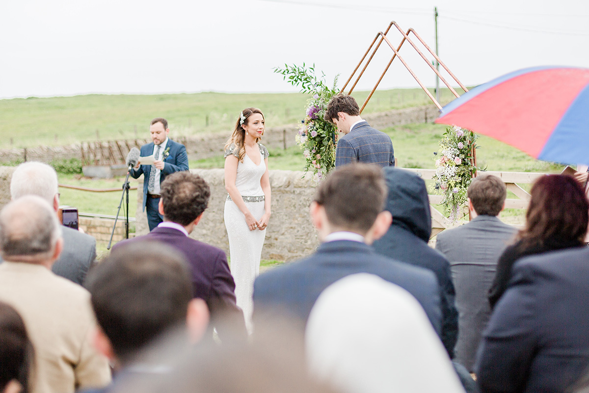 bride and groom in field with copper wedding arch