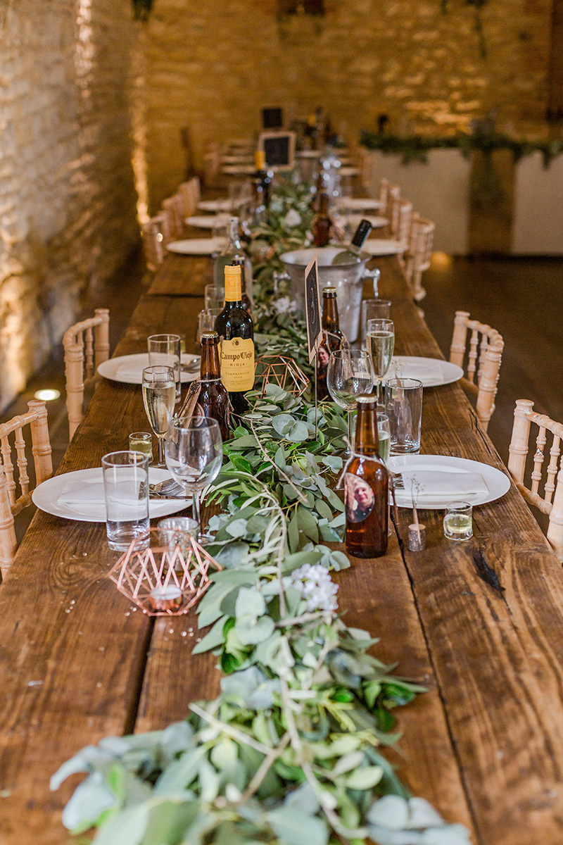 long wedding table set for meal with green foliage down the middle