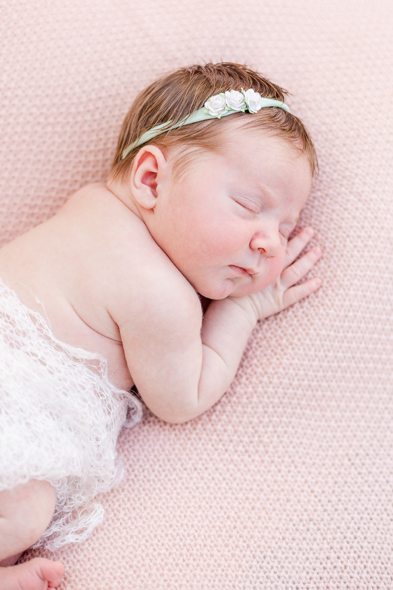 newborn baby girl asleep on pink blanket wrapped in lace blanket