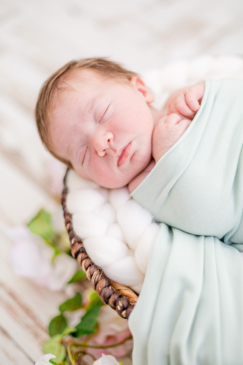 closeup of newborn baby girl asleep on round basket