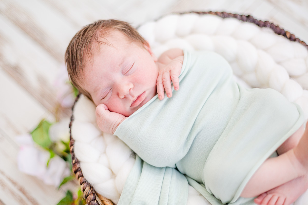 newborn baby girl asleep in round basket