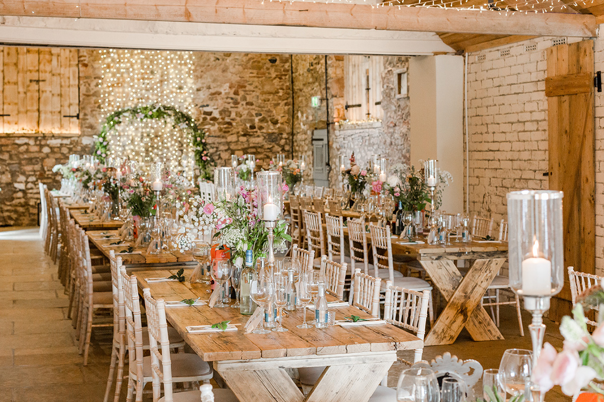 long wedding tables with flowers and arch way visible at the end of table