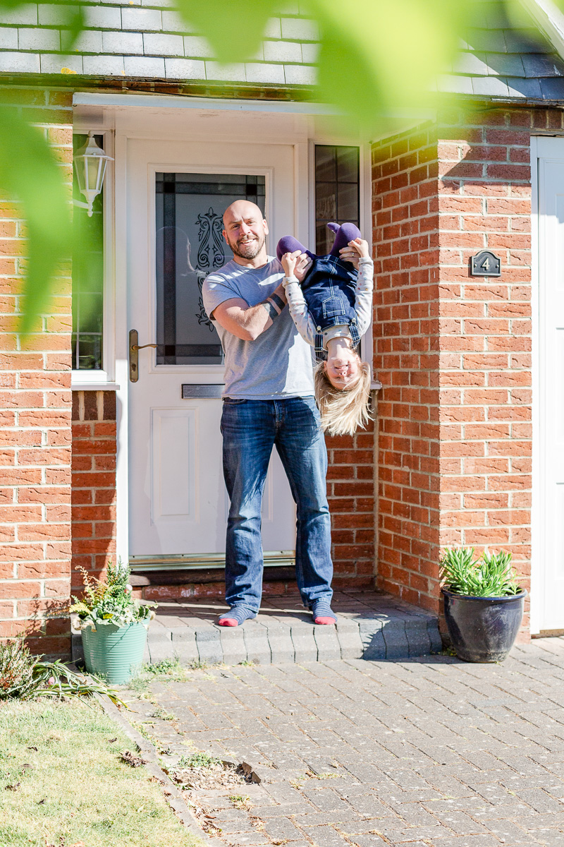 Daddy holding daughter upside down on doorstep