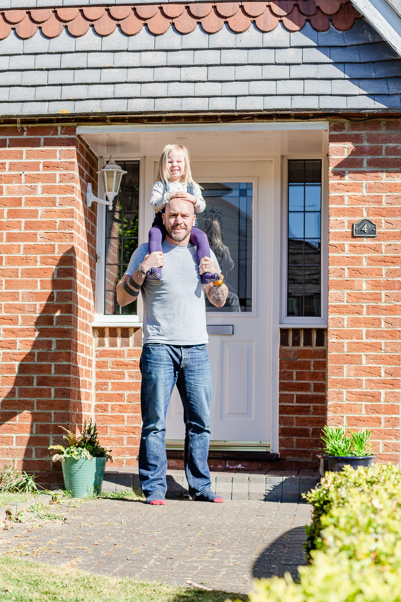 daddy holding daughter on shoulders on doorstep