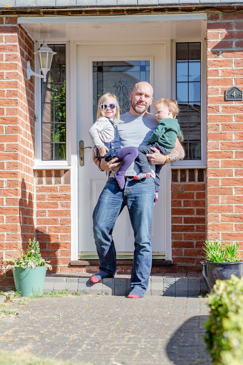 Daddy stood on doorstep with daughter and son on hips