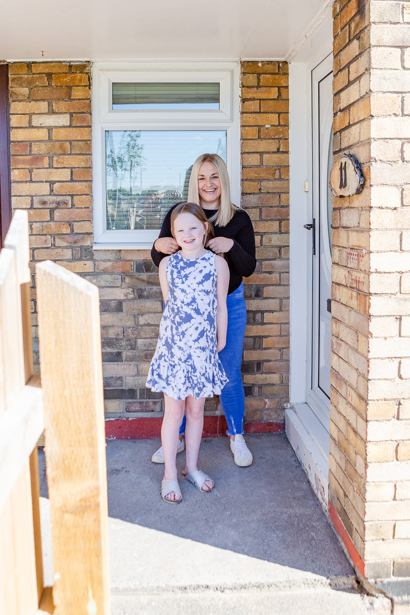 a mummy playing with daughter hair on doorstep