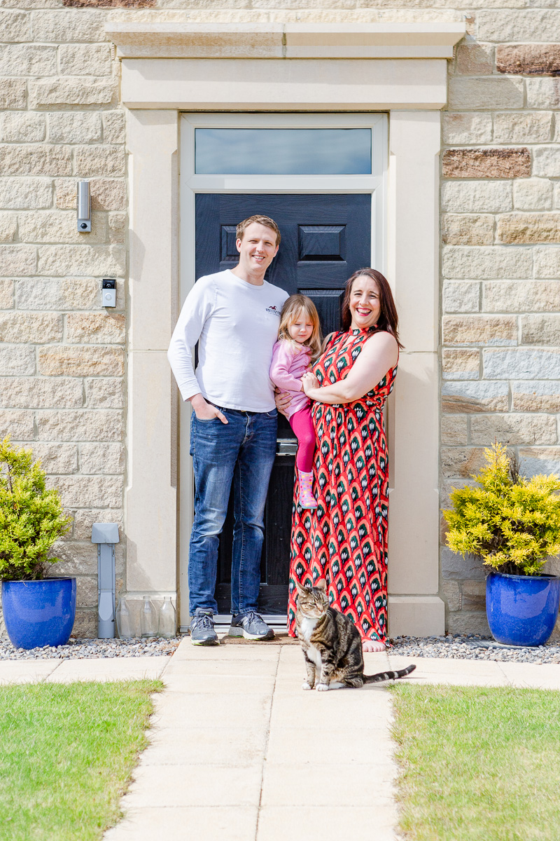 a mummy and daddy with daughter and cat on doorstep