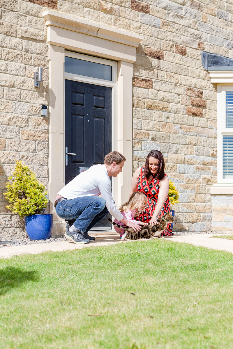 family playing with cat on doorstep