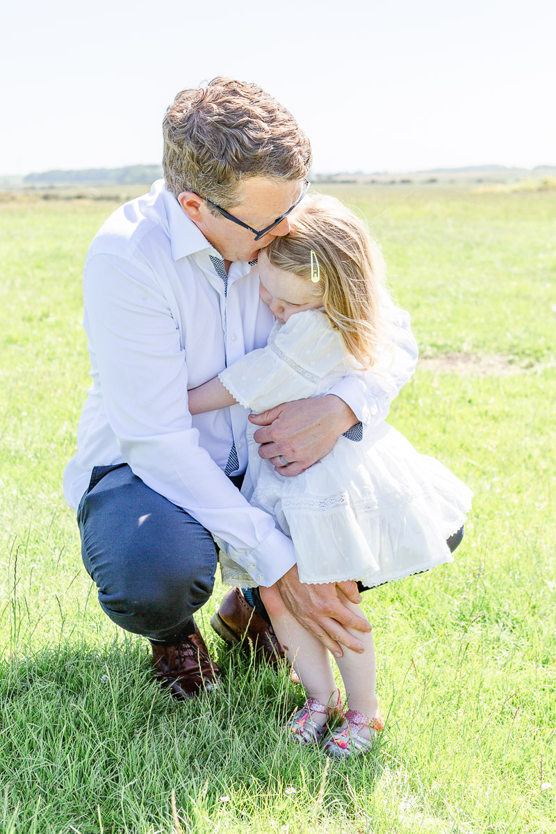 dad cuddling daughter in field