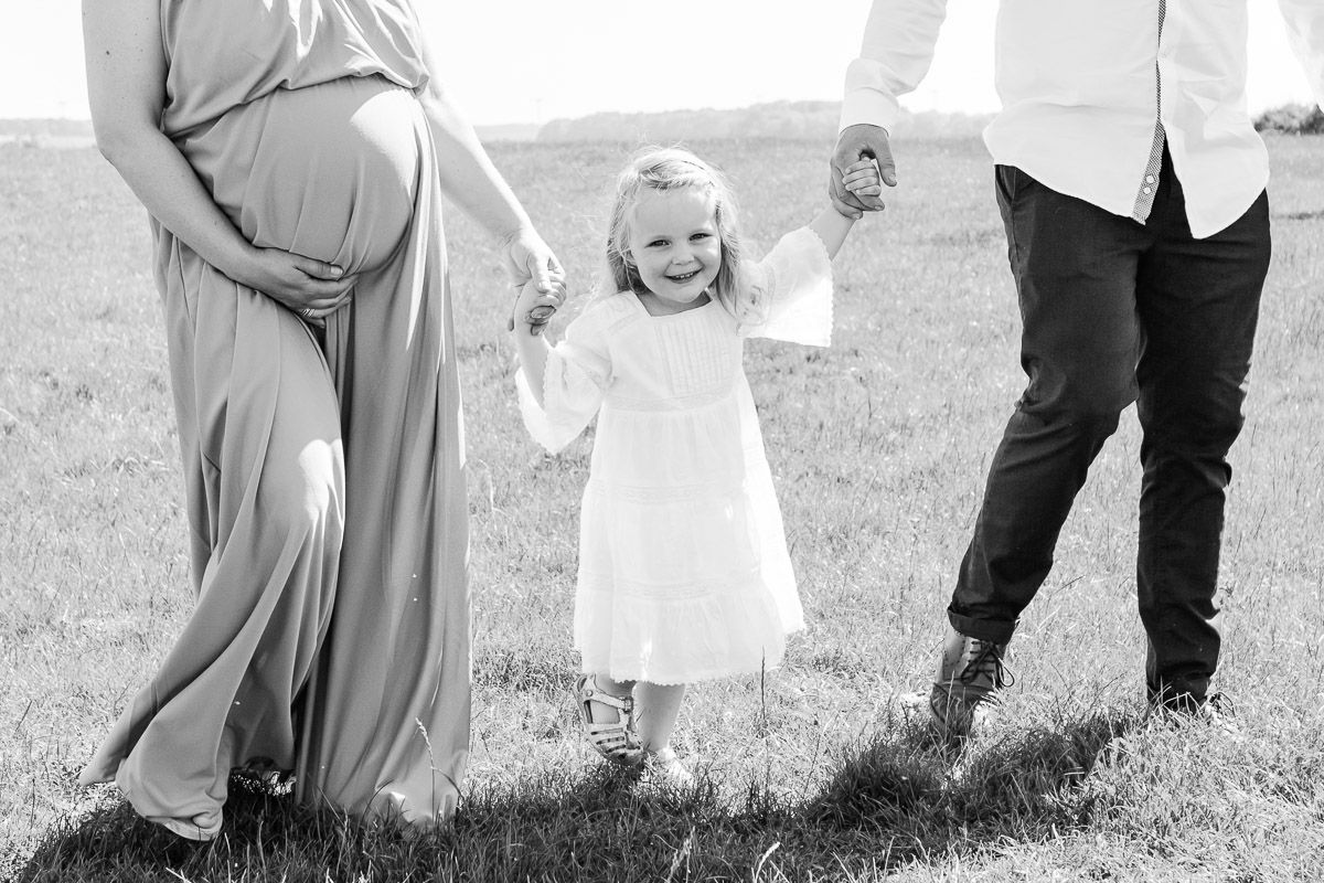 daughter holding hands with parents in field