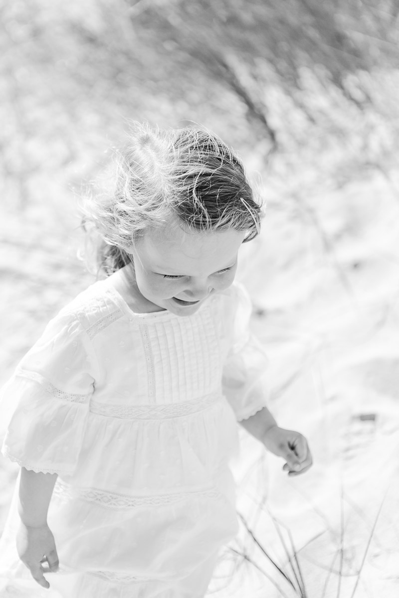 black and white image of toddler walking in sand