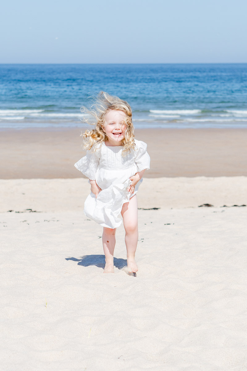 toddler laughing at camera with hair blowing in the wind