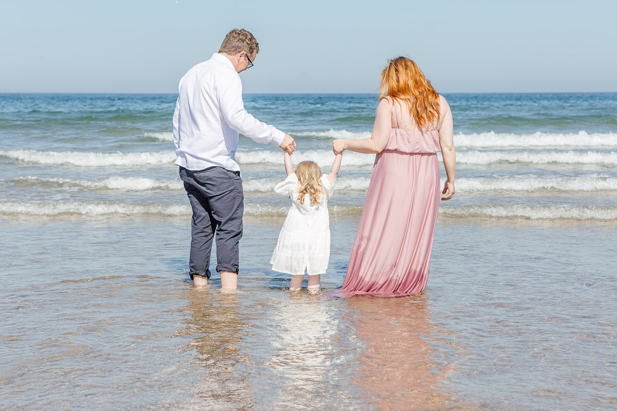 family jumping waves facing away from camera