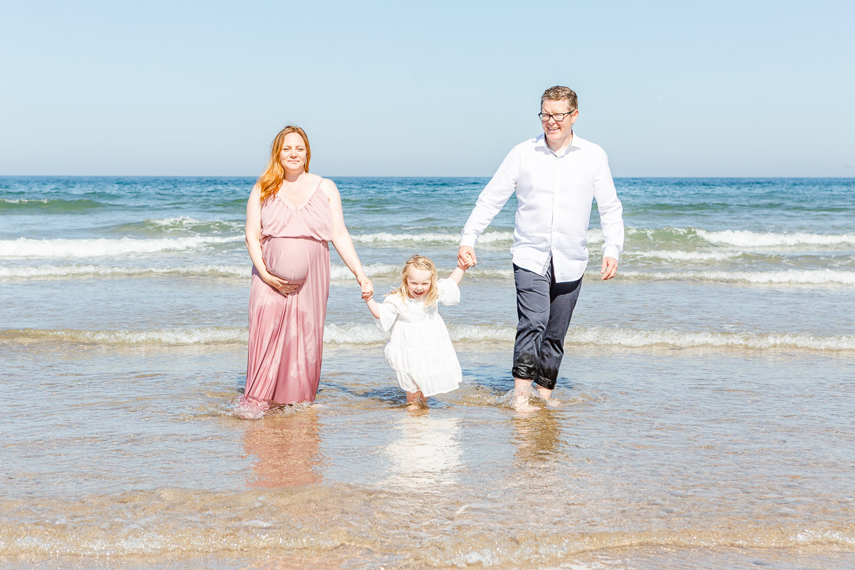 family paddling in sea holding hands