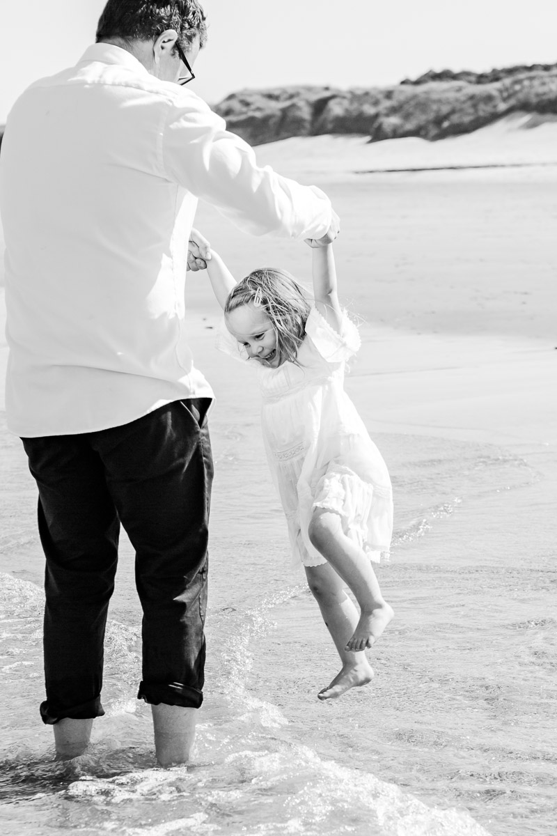 daddy and daughter playing in the sea black and white